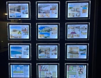 Suspended hanging LED window display installed in real estate office window showcasing property listings